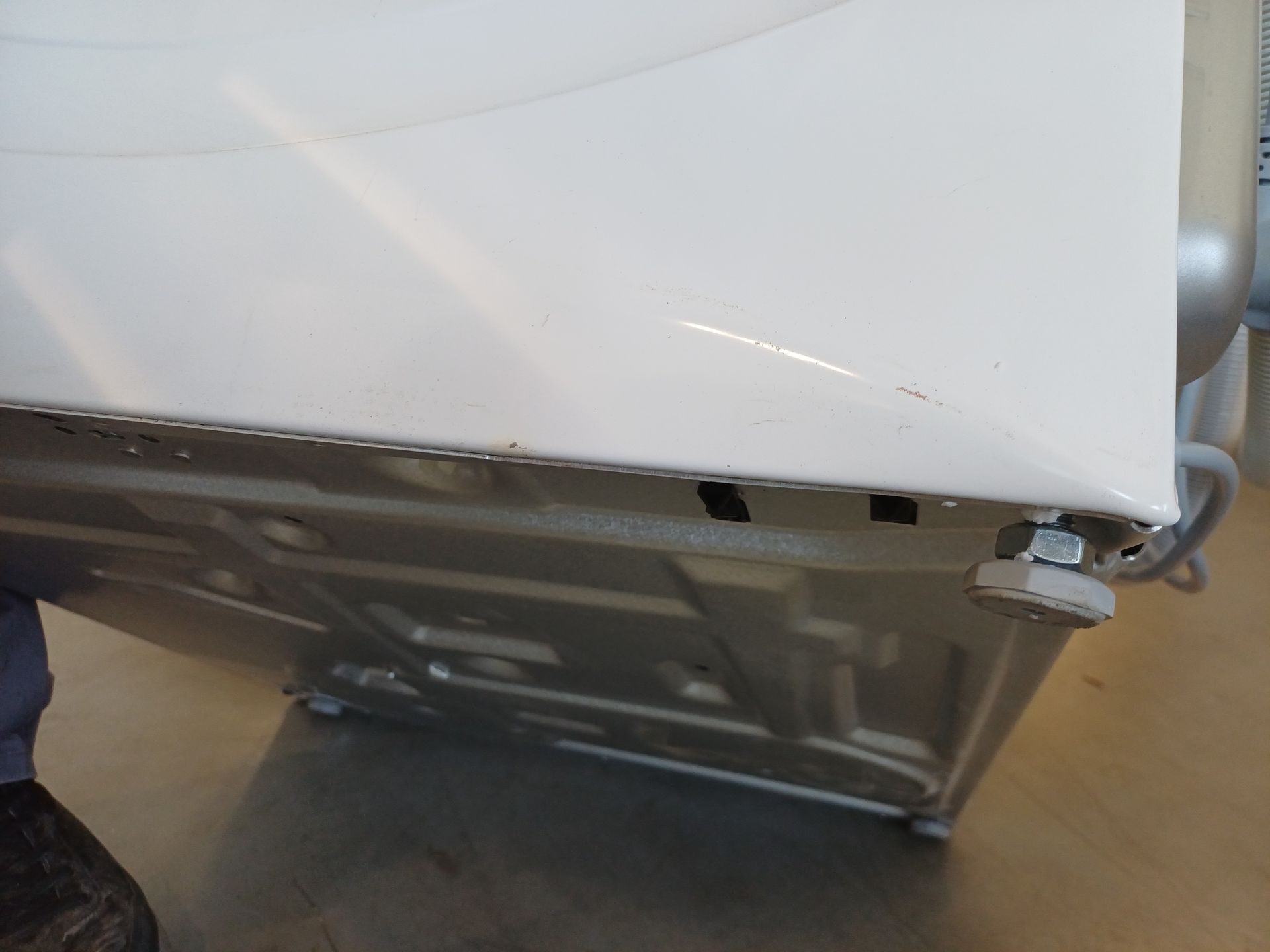 Waschmaschine, vorderes linkes Panel, Metallkörper, weiße Außenhaut, Bedienknopf